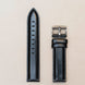 Black leather watch strap on a light beige background